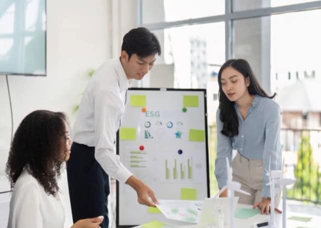 Tre personer diskuterar KPI-diagram på ett ESG-inspirerat analysmöte